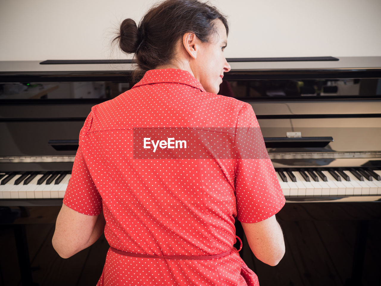 Rear view of woman playing piano at home