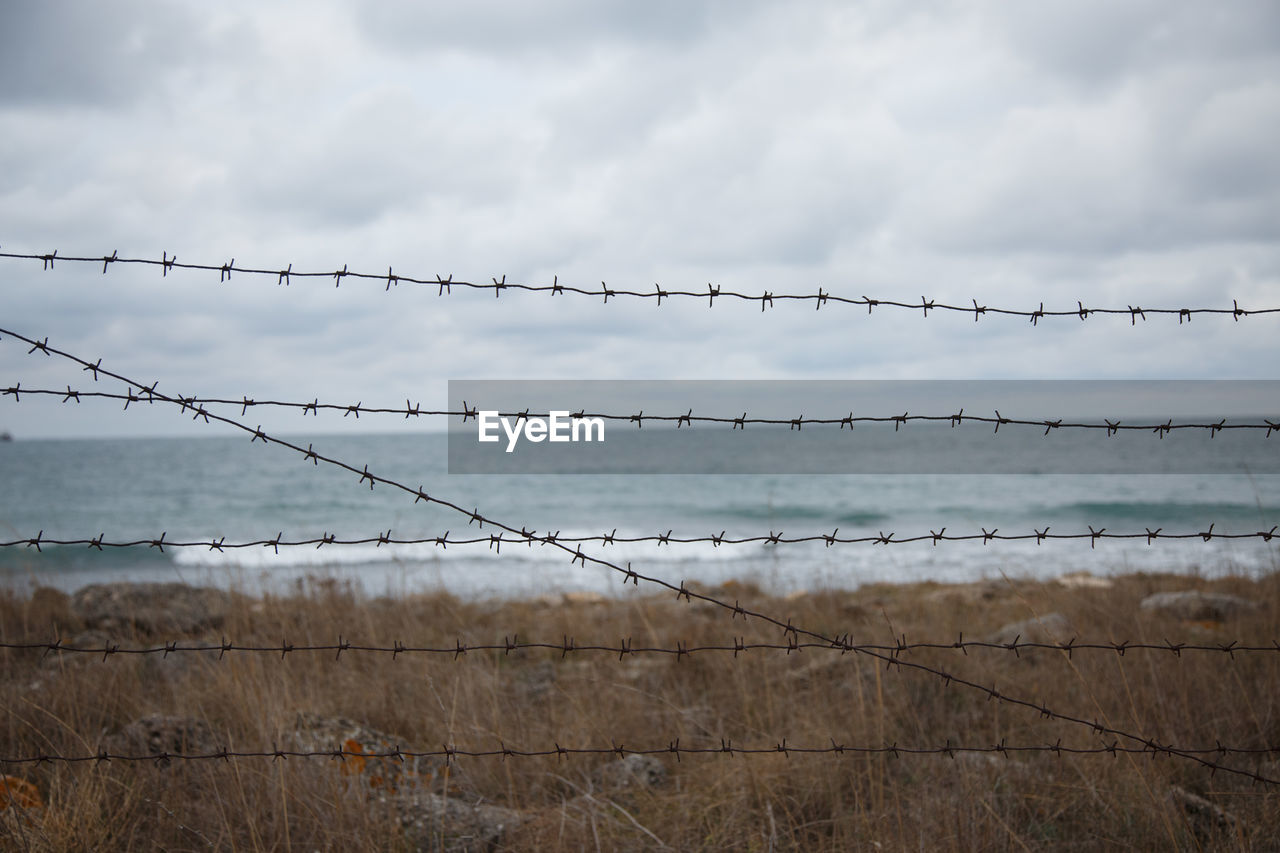 Travel restrictions. the sea beyond the fence with barbed wire