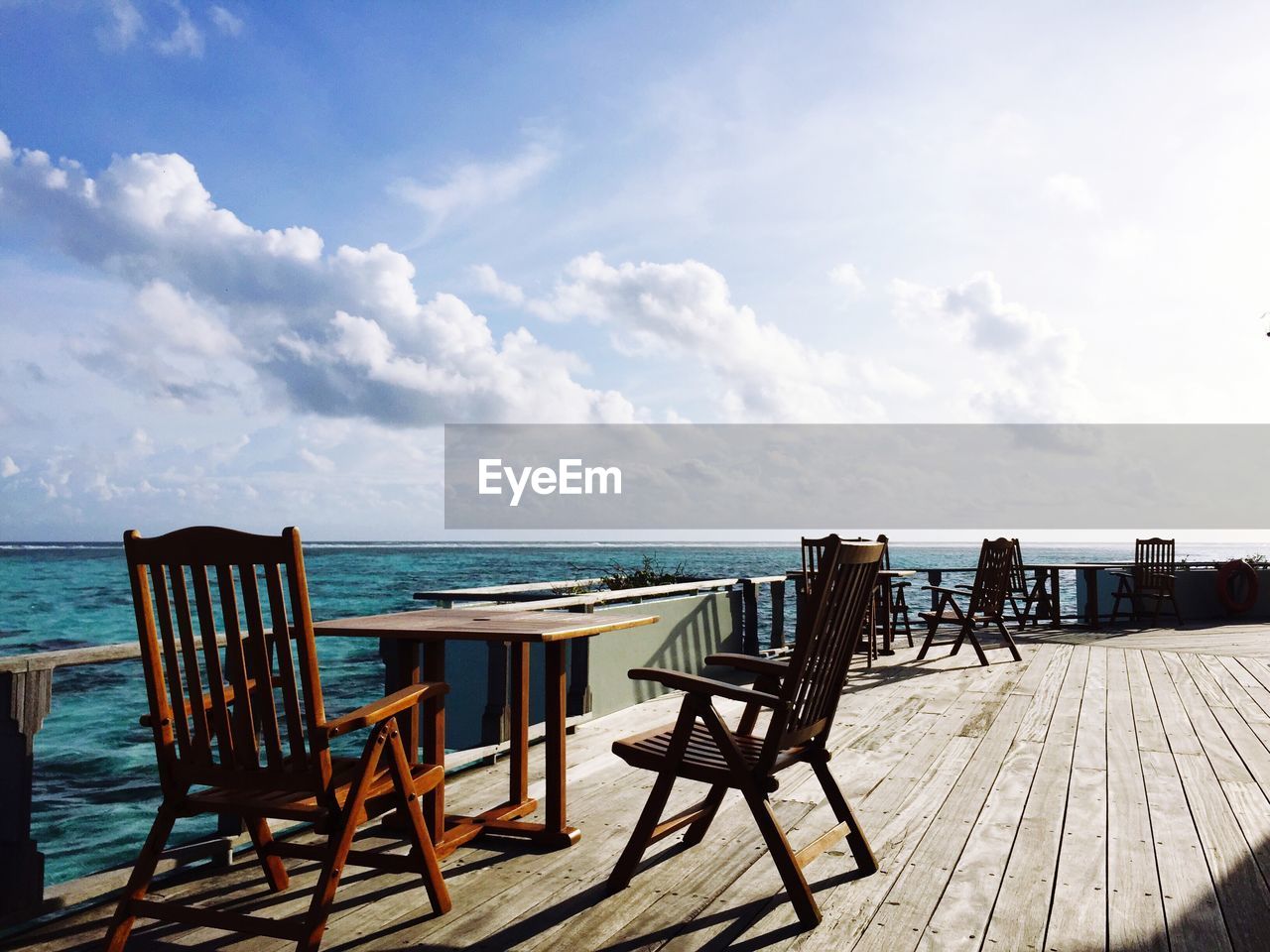 Chairs and tables at beach against sky