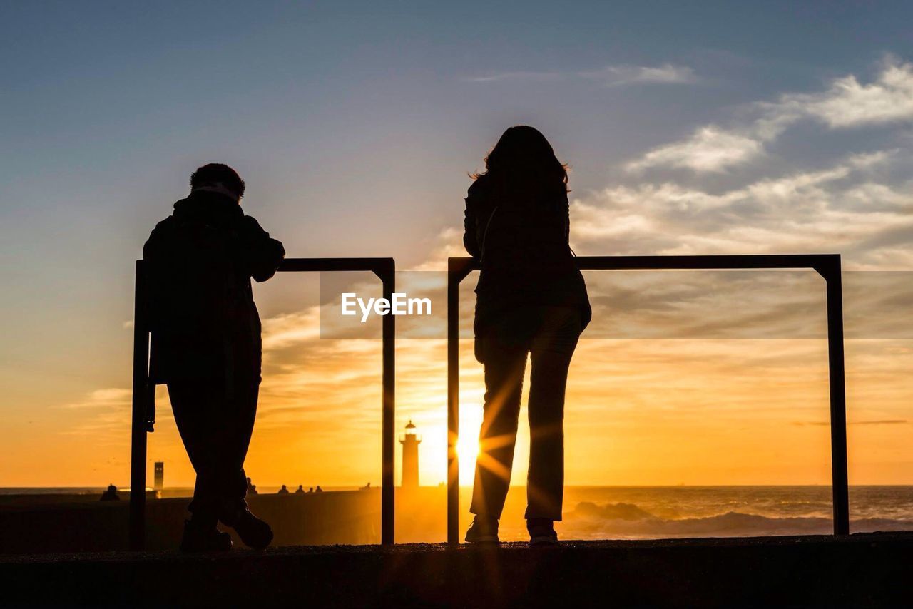 Silhouette of people looking at sea