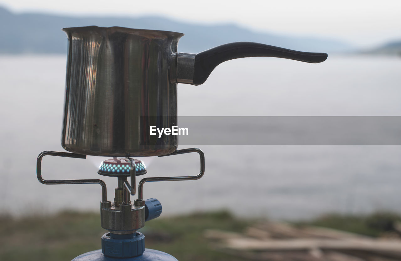 CLOSE-UP OF FAUCET AGAINST WATER