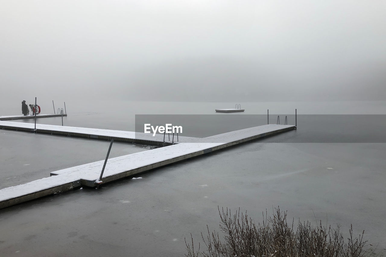 Pier over lake against sky during winter