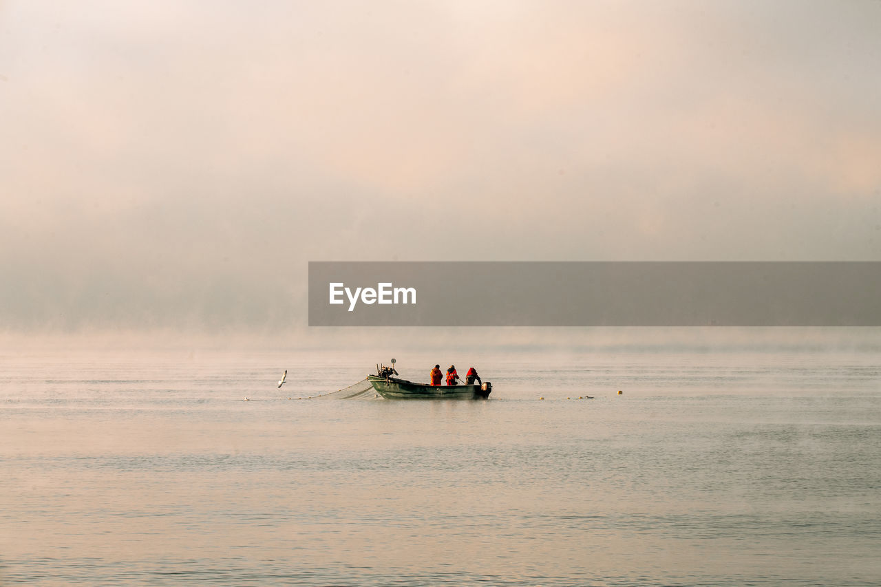 PEOPLE ON BOAT AGAINST SEA AGAINST SKY