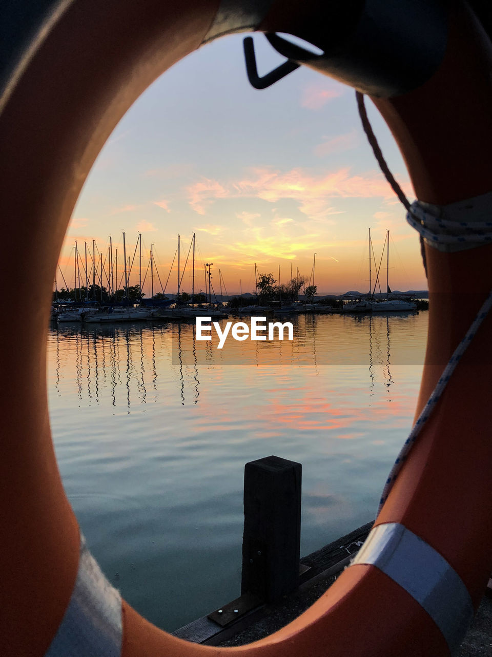 Lake seen through life belt against sky during sunset