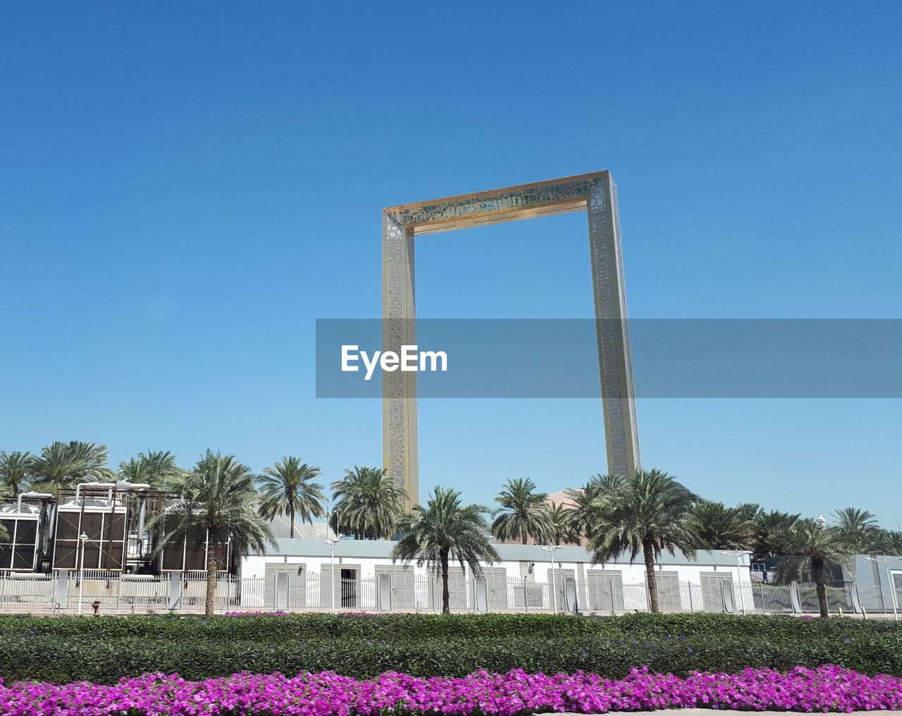 BUILT STRUCTURE AGAINST BLUE SKY WITH TREES IN FOREGROUND