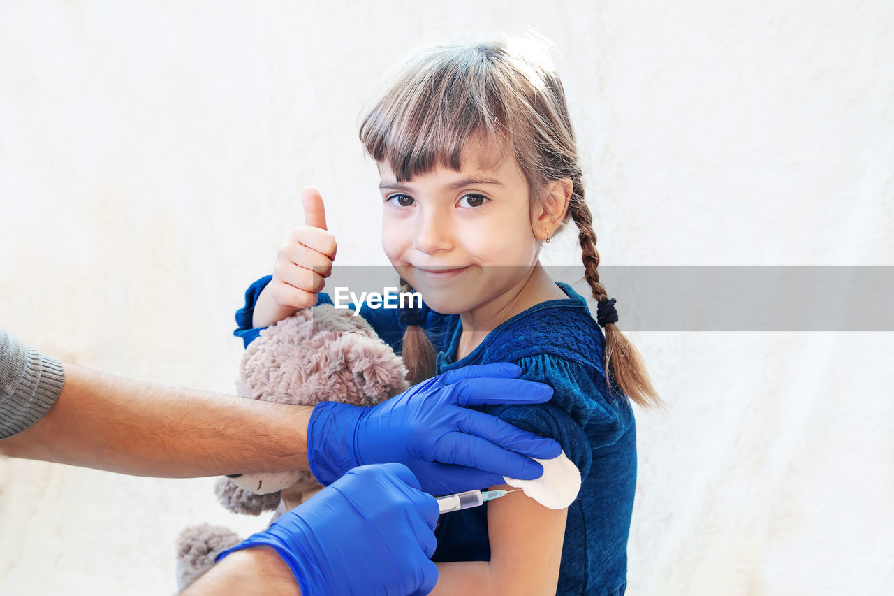 Hands giving vaccination to girl