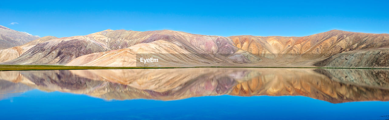 Reflection of mountains in lake against blue sky