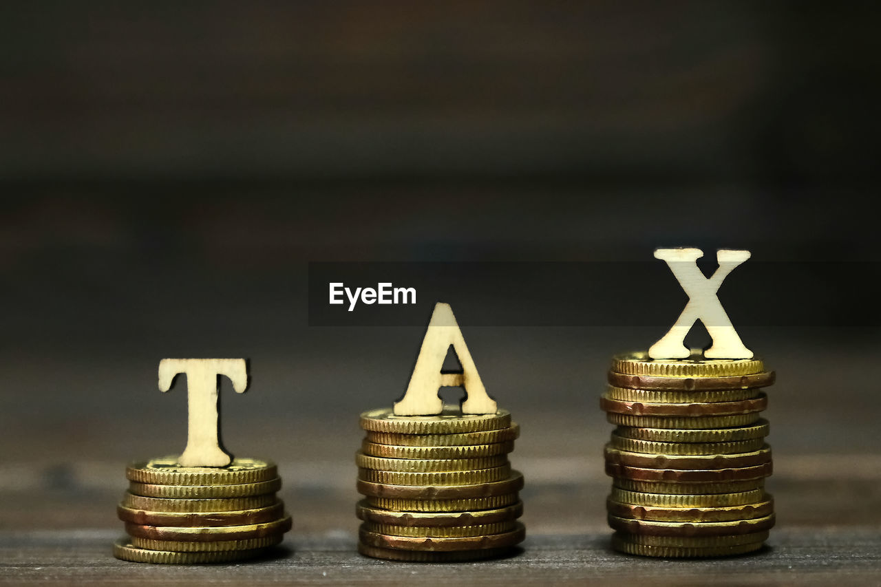 Close-up of stack coins with tax letters on table