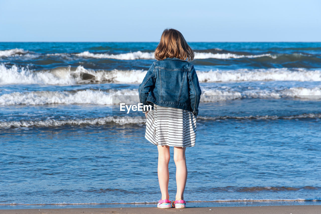 Rear view of girl standing at beach