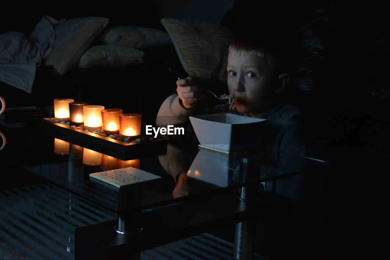 Young boy eating in living room at night