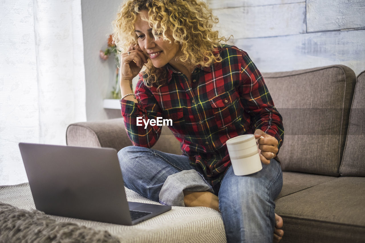 Smiling woman using laptop sitting at home