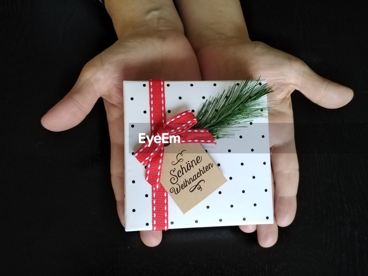 Happy christmas, german frohe weihnachten. hands holding christmas gift box. flat lay