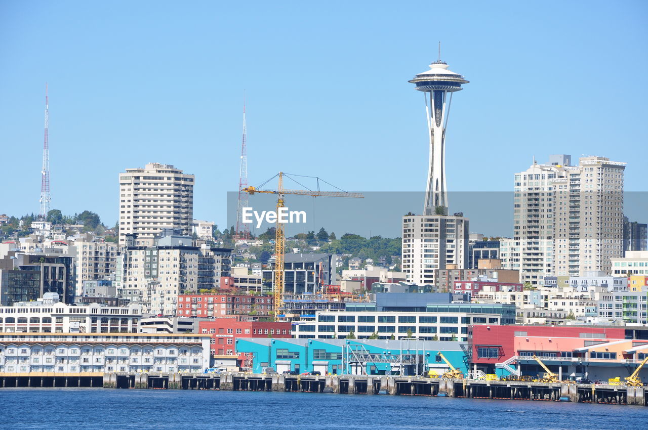 Space needle in city by sea against clear sky