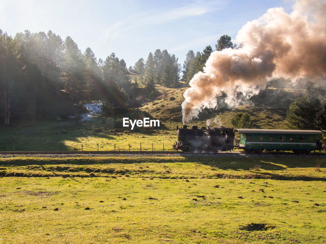 Smoke emitting from train on field against sky