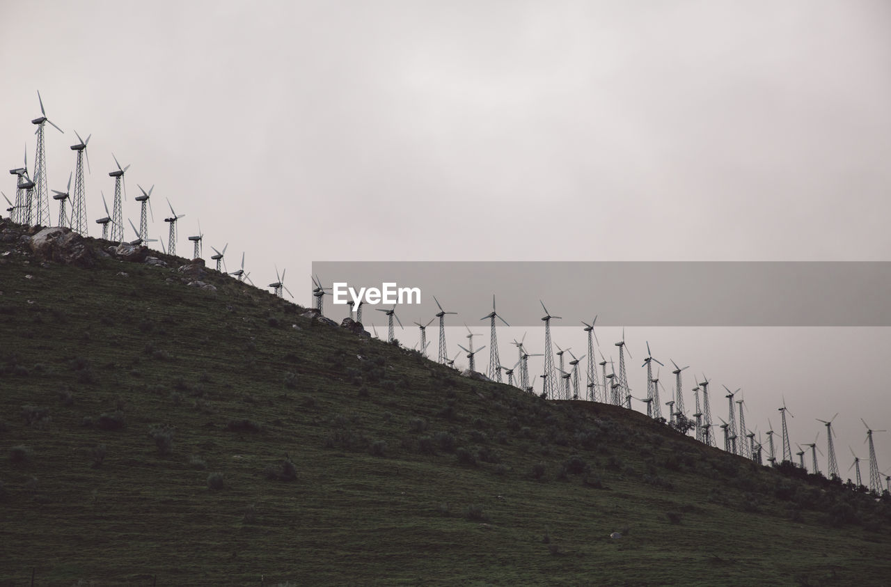 Low angle view of wind turbines on hill