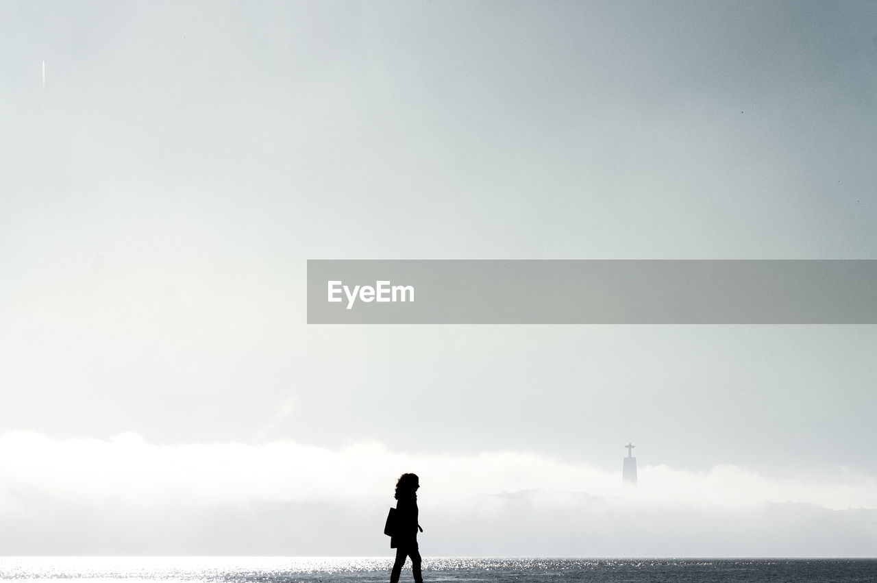 Silhouette man standing on beach against sky