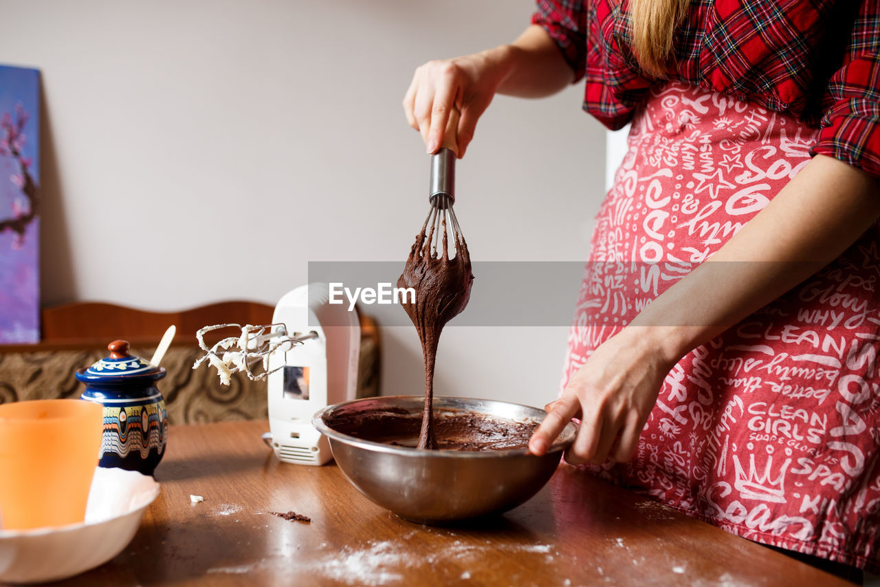 The process of mixing and preparing chocolate cupcakes by young lady