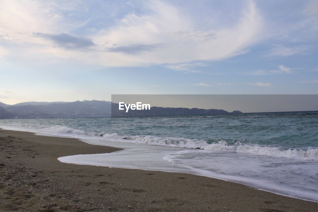 View of calm beach against mountain range