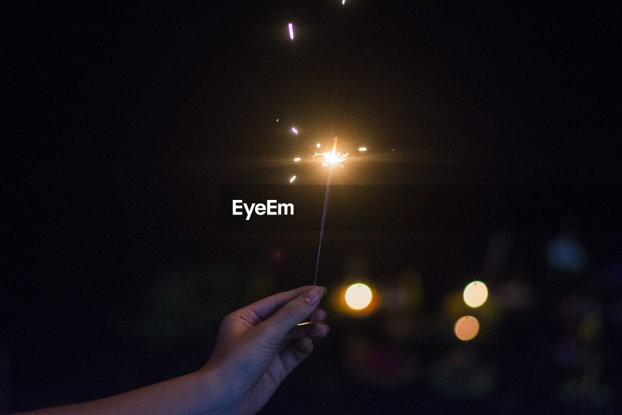 PERSON HOLDING ILLUMINATED LIGHT AT NIGHT