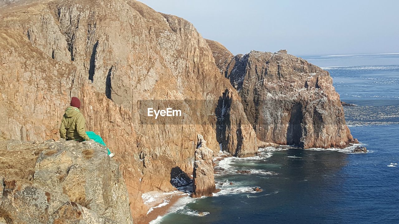 Mid distance view of person sitting on rock formation