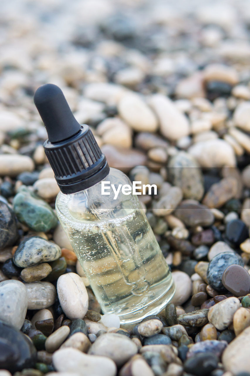 Cosmetic serum in a glass bottle with a pipette on stones