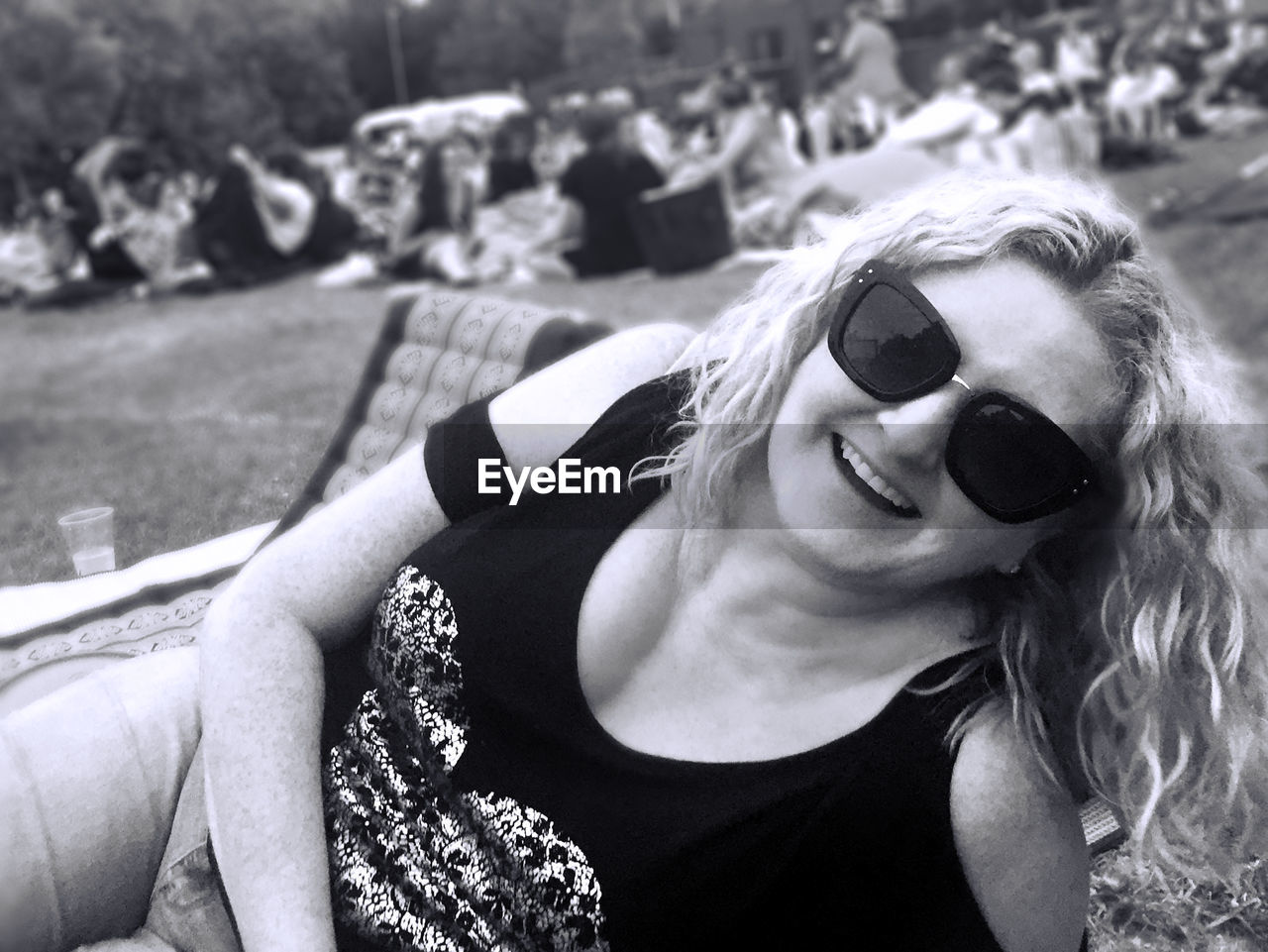 Close-up of smiling woman relaxing on field at park