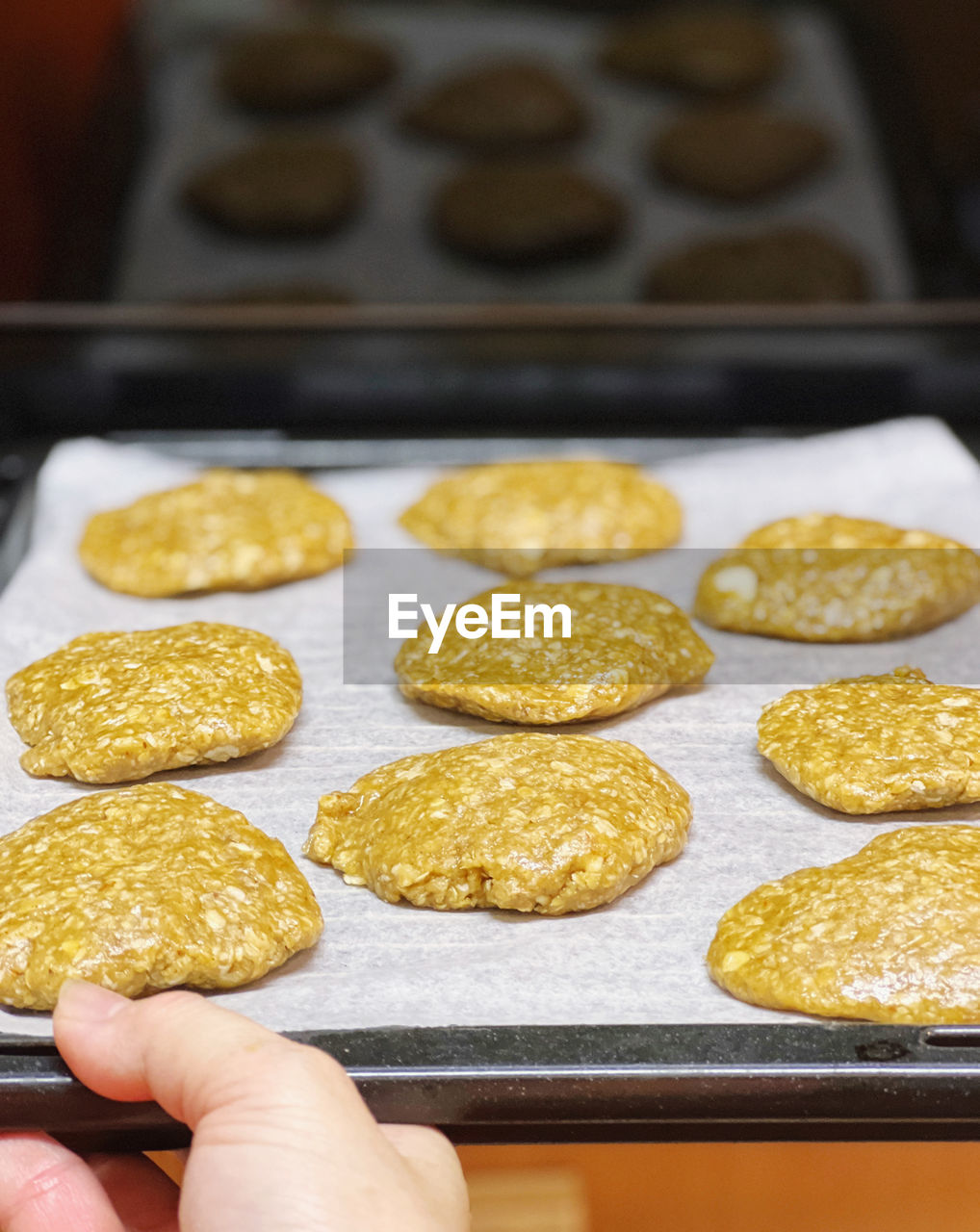 Cropped hand holding cookies to the oven