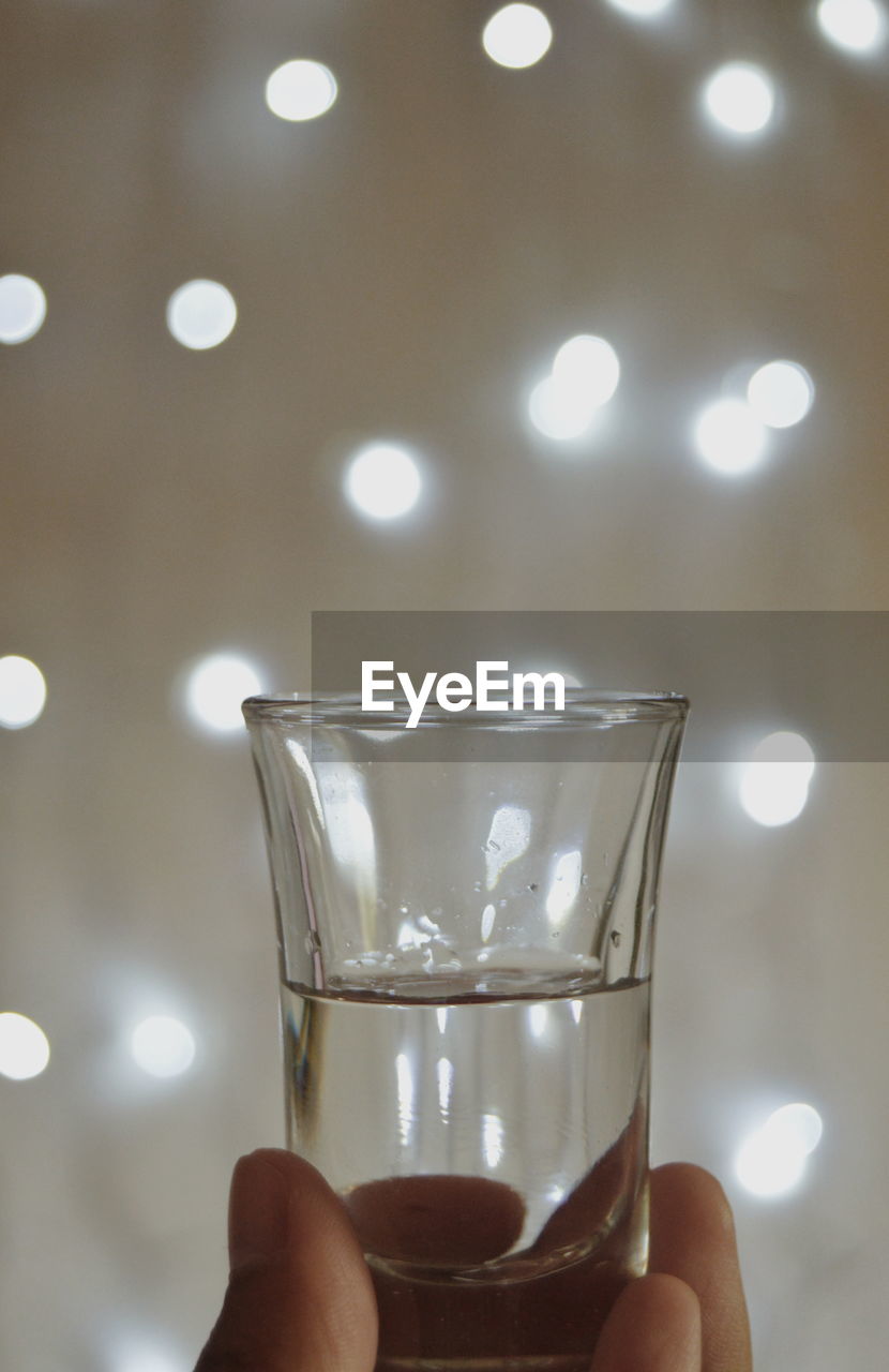 Close-up of hand holding drink against lights