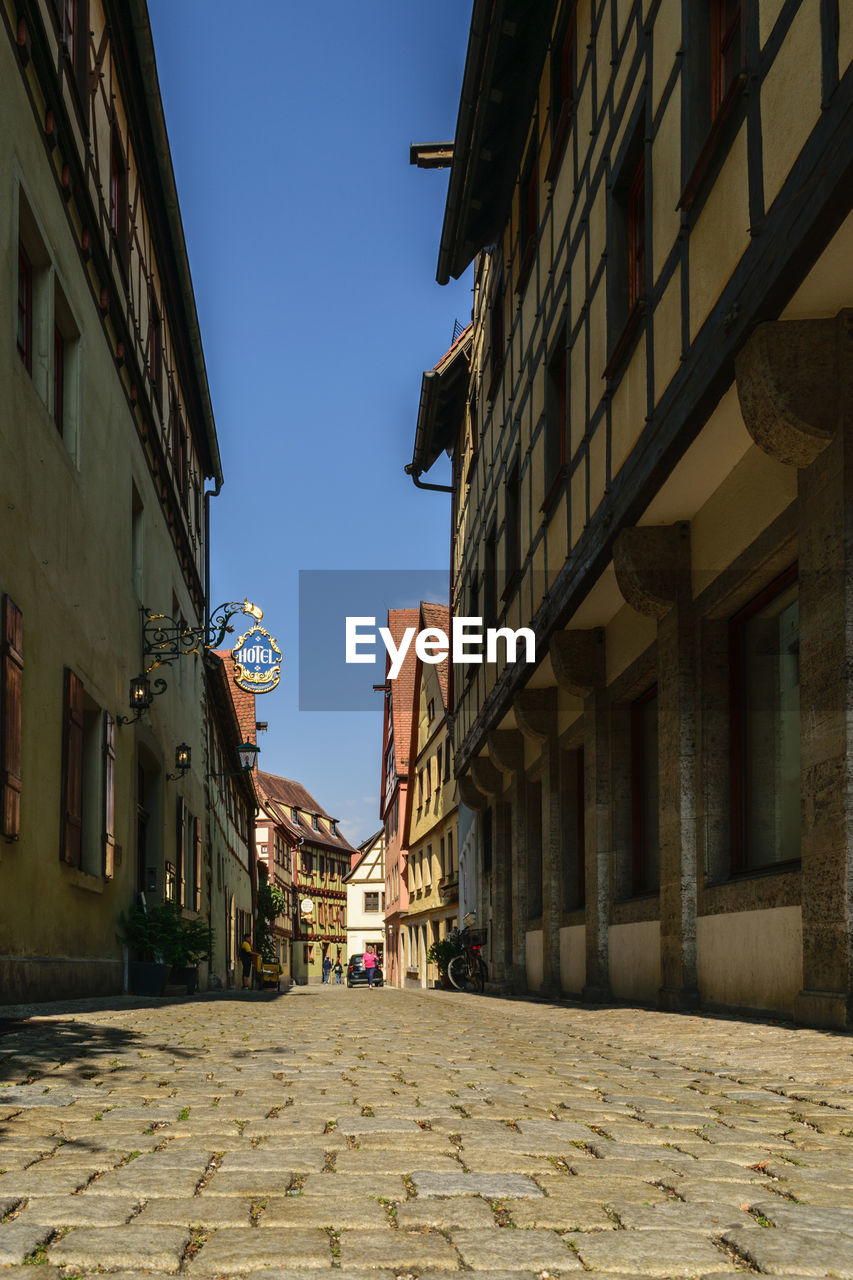 FOOTPATH AMIDST BUILDINGS AGAINST SKY