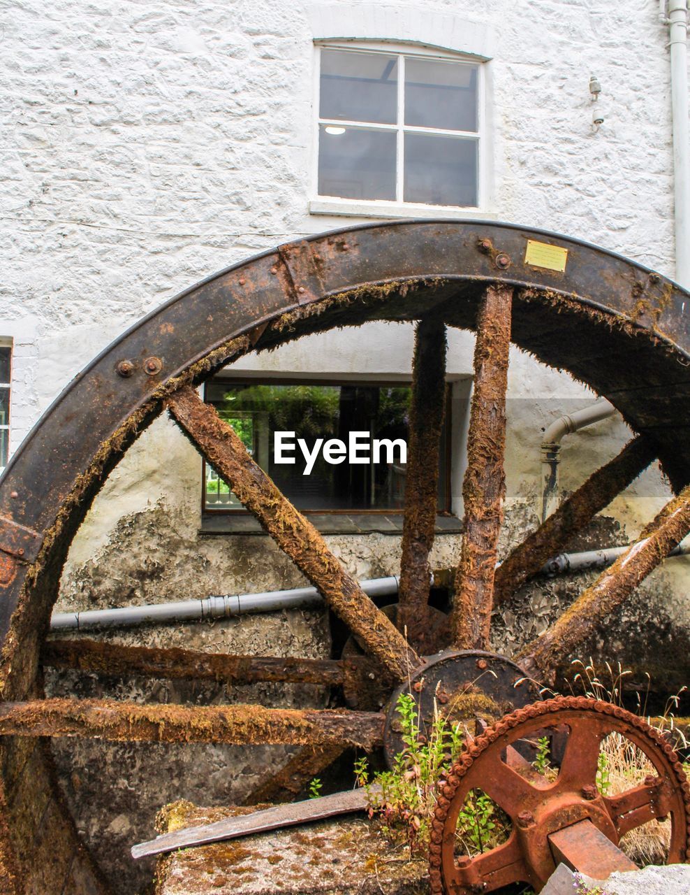 Rusty water wheel against building