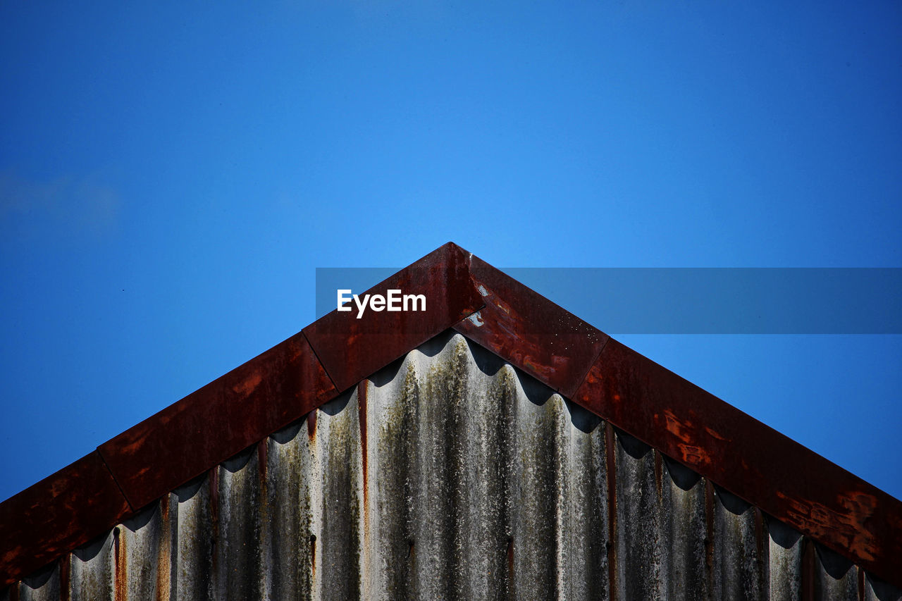 LOW ANGLE VIEW OF RUSTY METAL AGAINST BLUE SKY