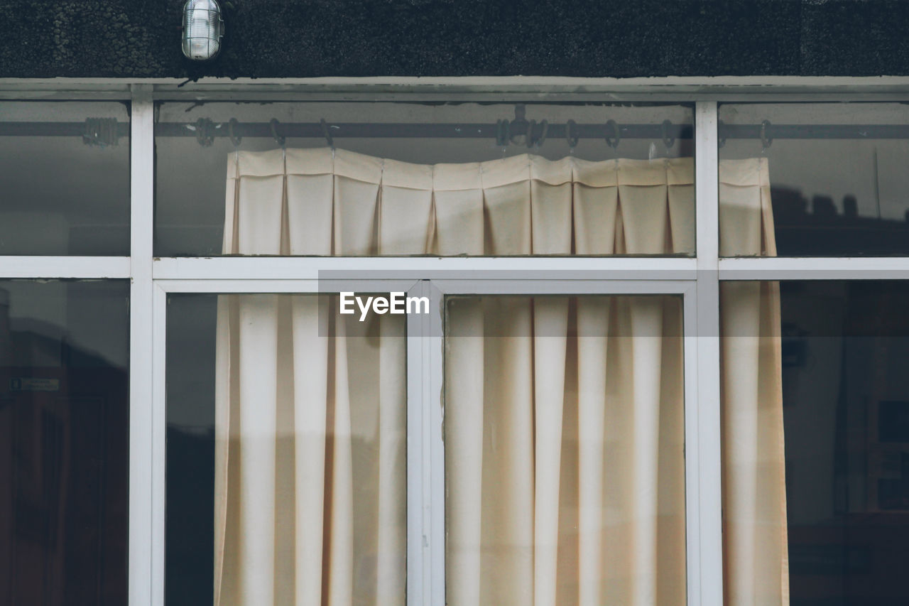 Detail of a window with old beige curtains.