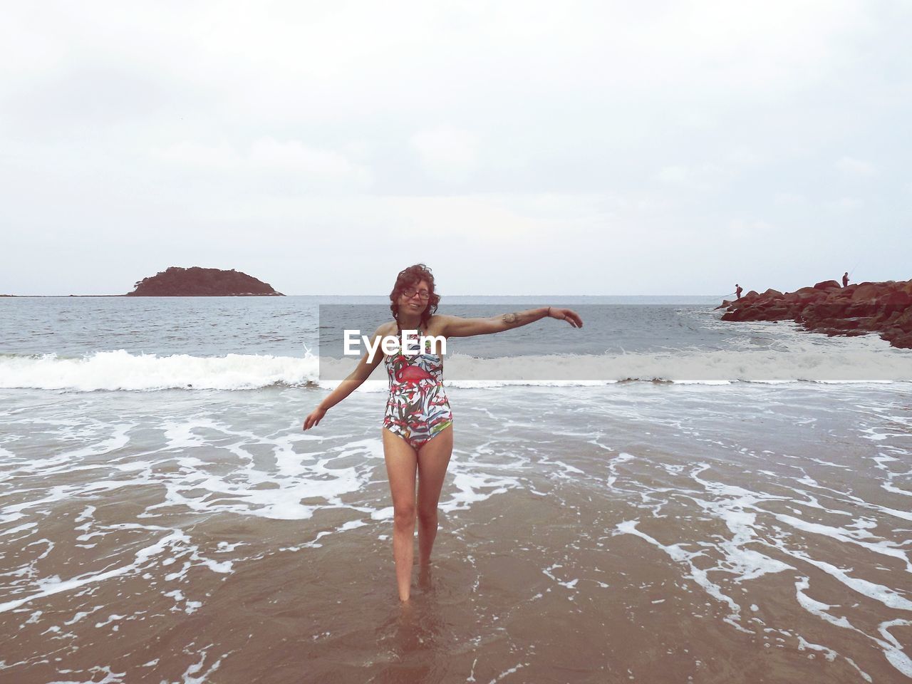 Smiling mid adult woman with arms outstretched standing at beach