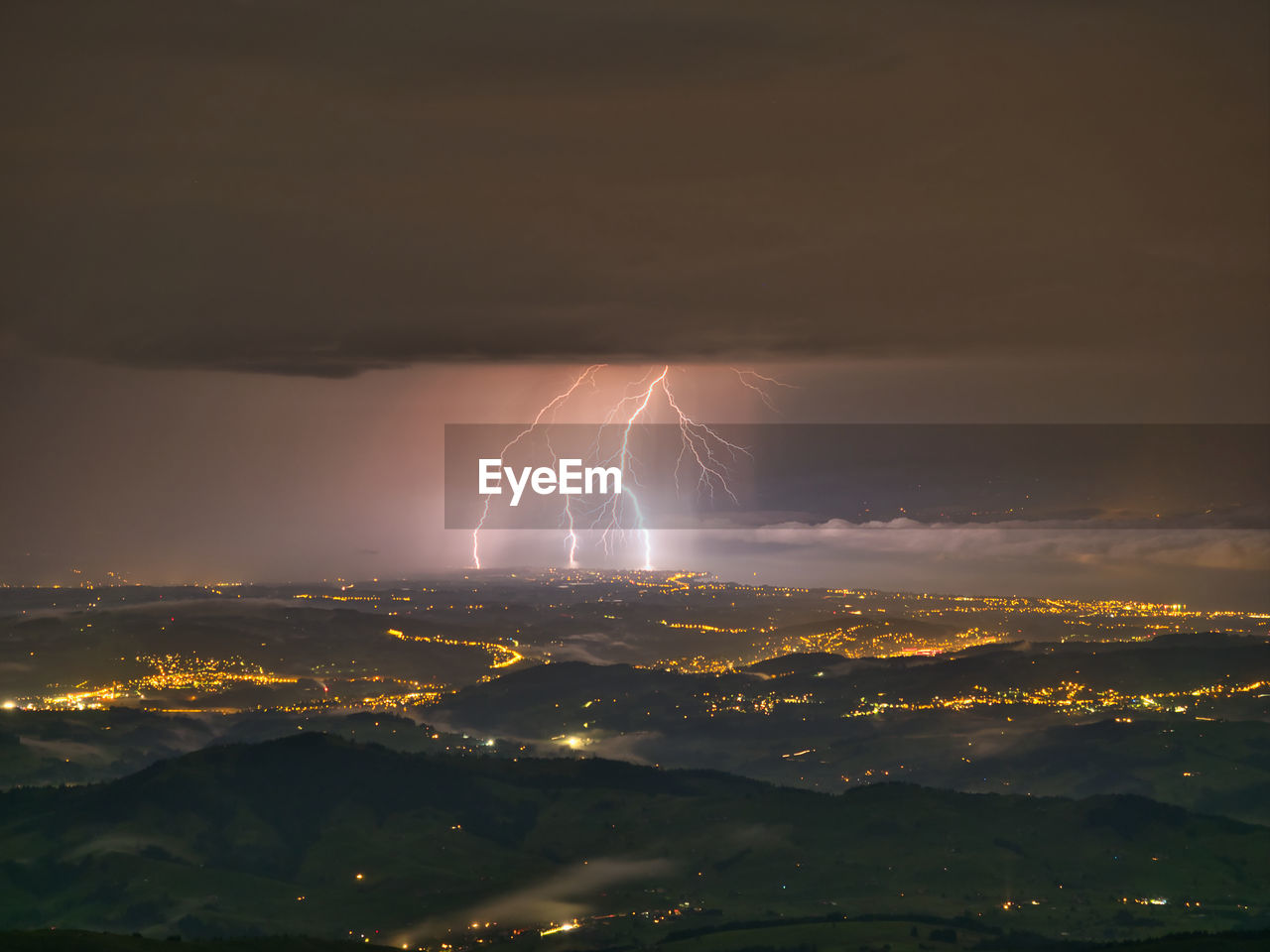 Lightning over illuminated city against sky at night