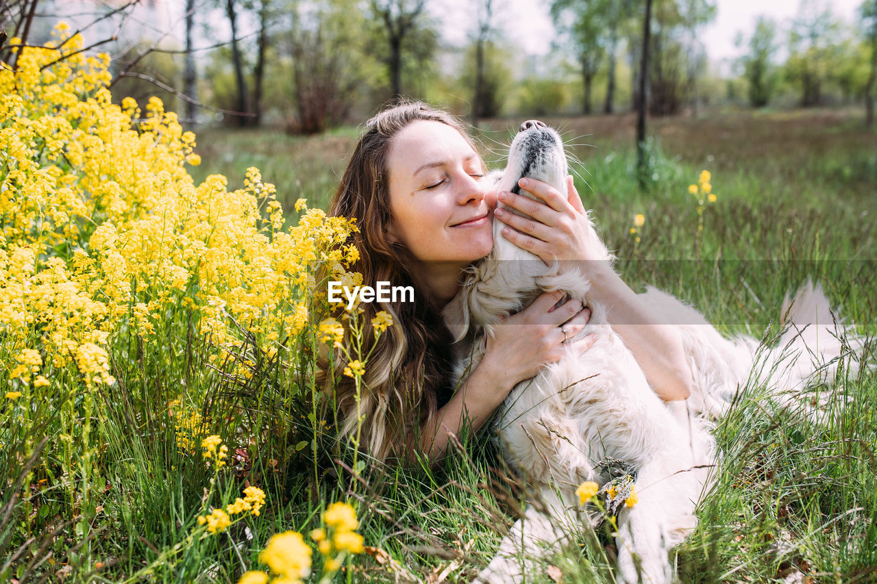 Young beautiful woman and her golden retriever dog having fun in summer