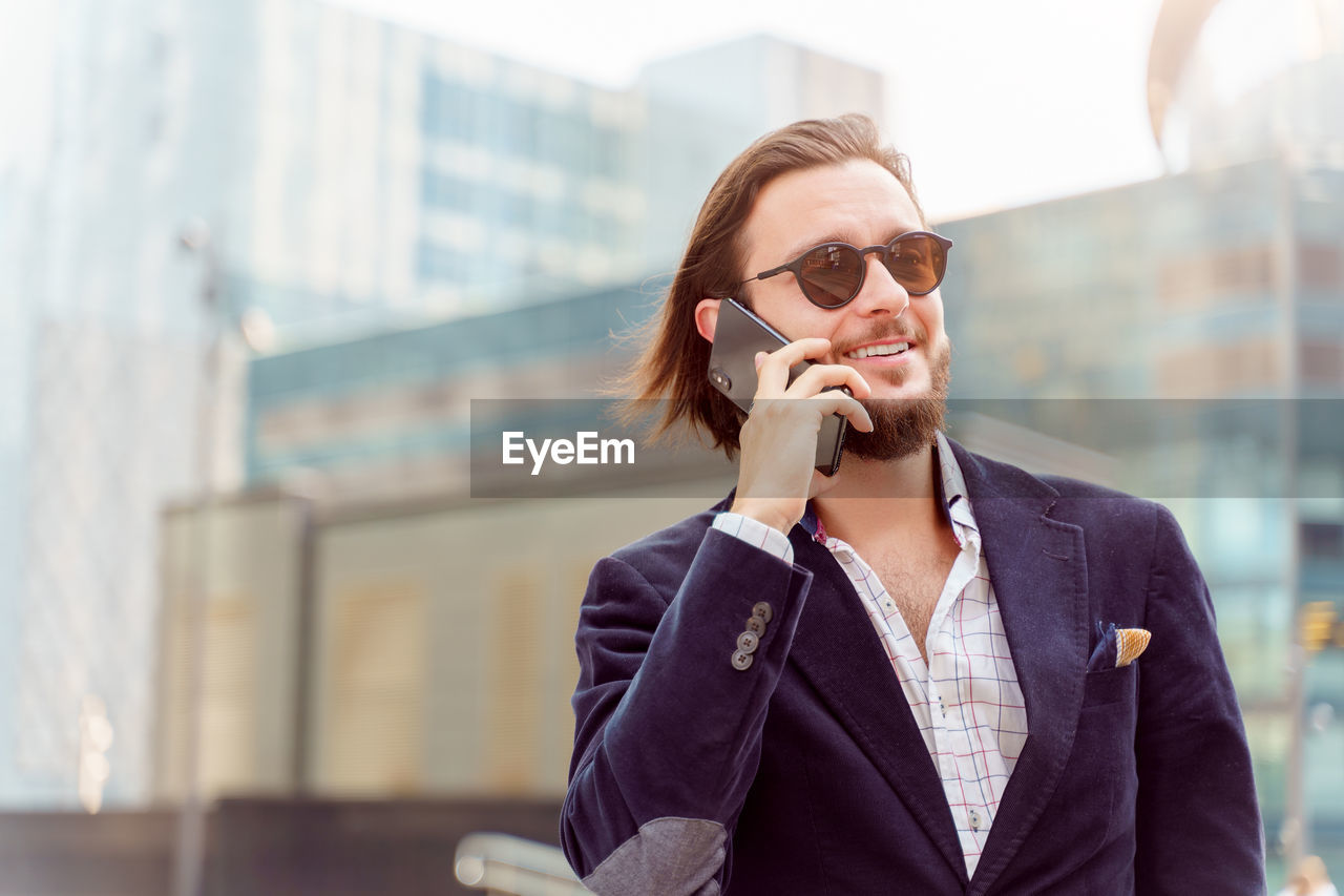 Smiling businessman talking on phone outdoors