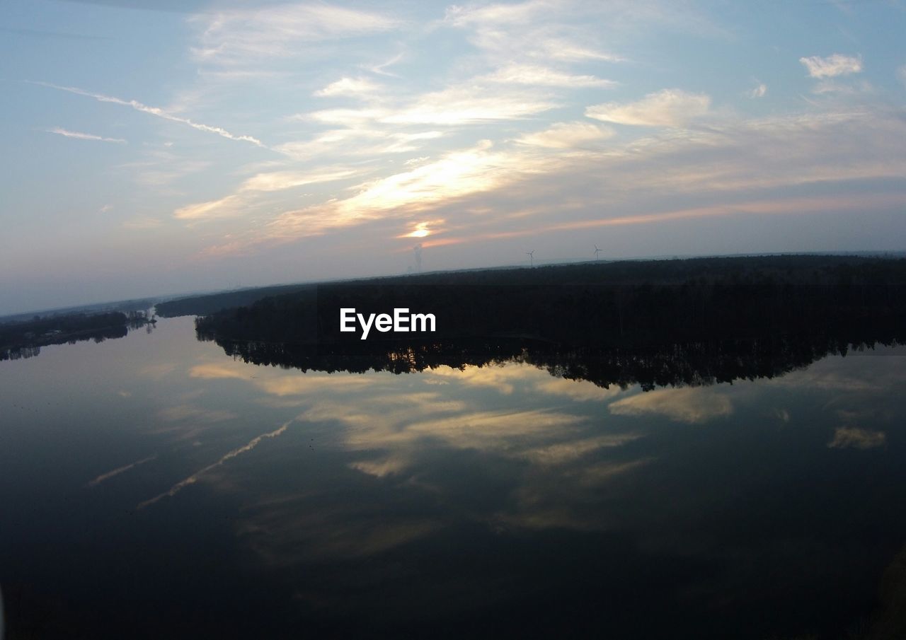 Reflection of trees against sky on calm lake at sunset