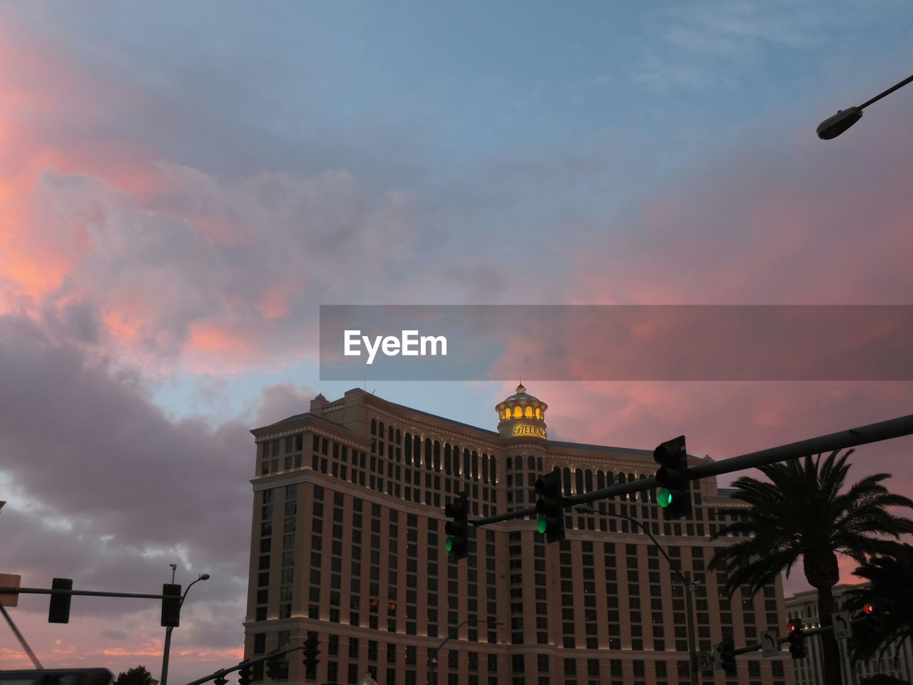 LOW ANGLE VIEW OF BUILDINGS AGAINST CLOUDY SKY AT SUNSET