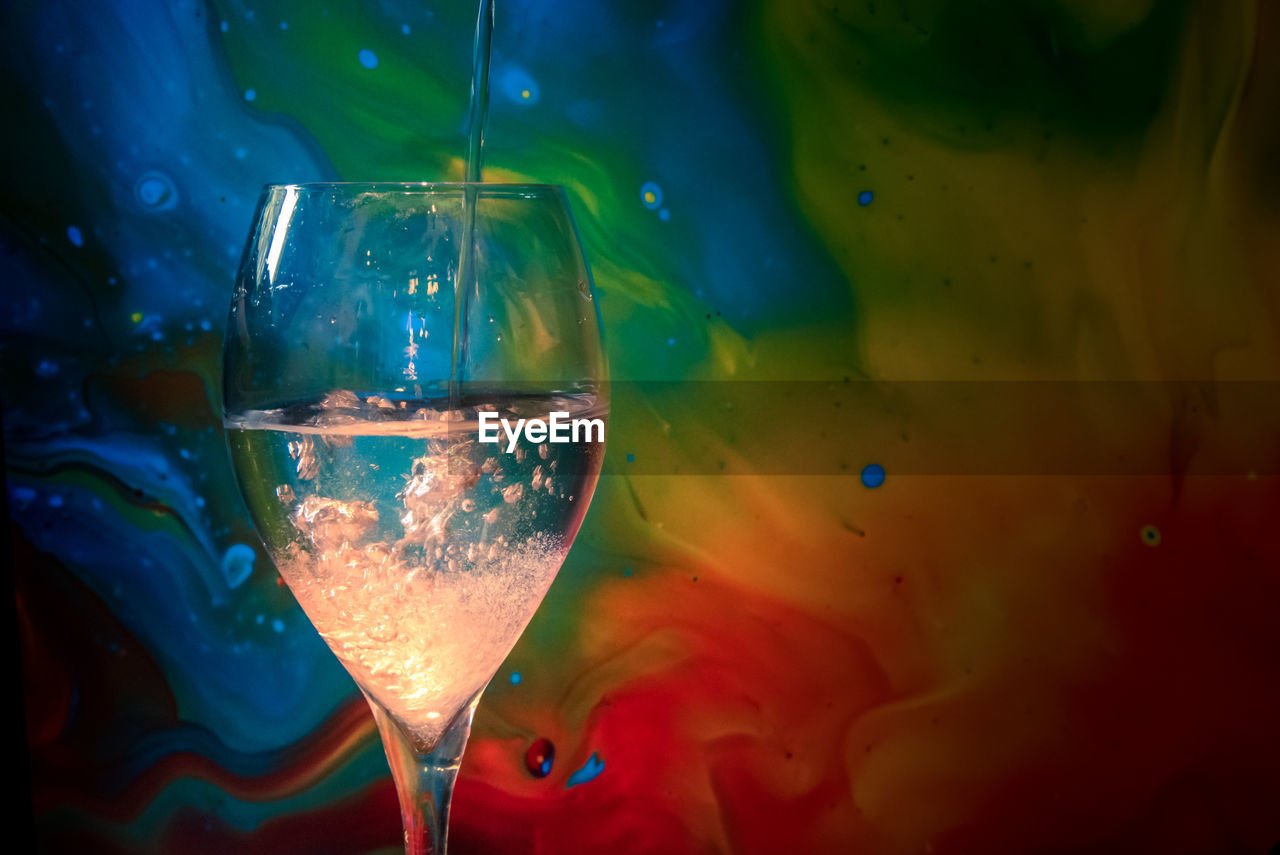 Pouring a drink on a multi-coloured background