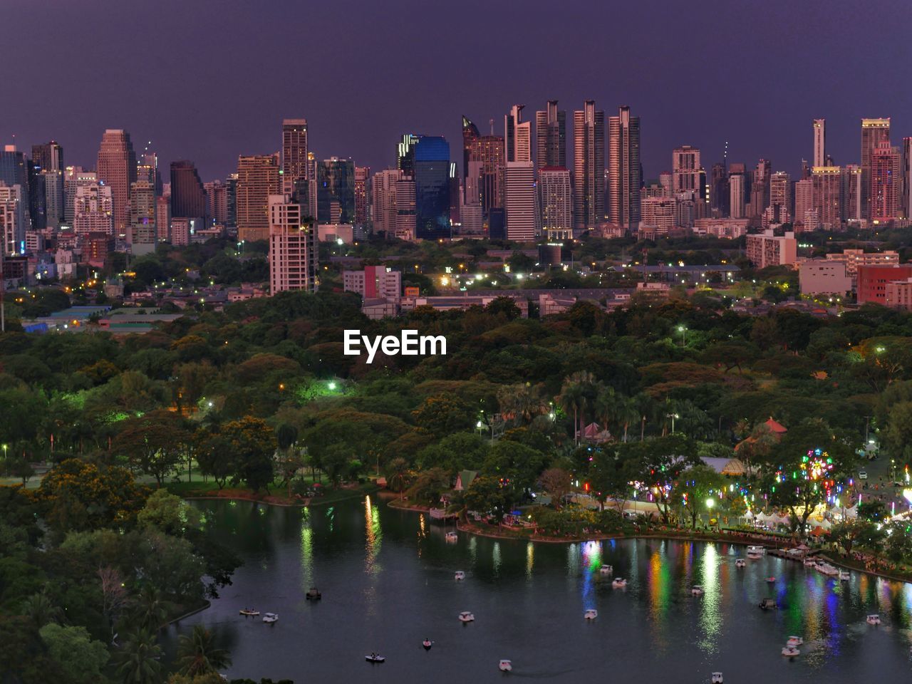 Illuminated buildings by river against sky in city at night