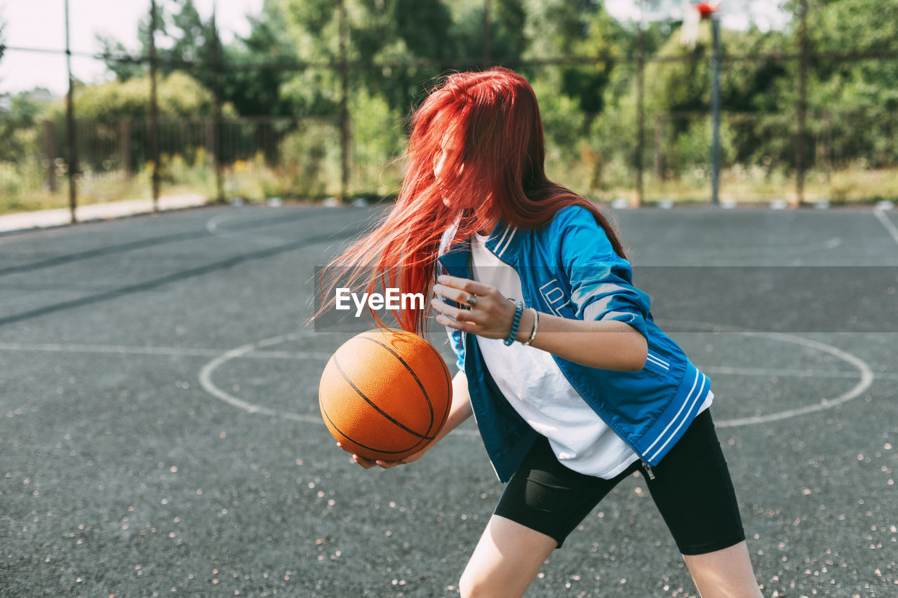 A beautiful teenage girl leads a basketball on a sports field, a girl learns to play basketball