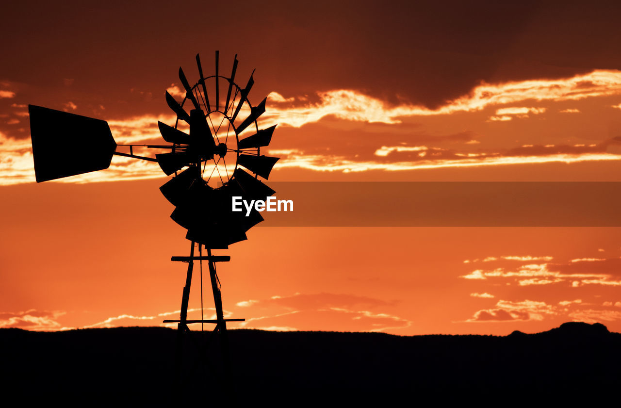 low angle view of silhouette man standing against orange sky during sunset