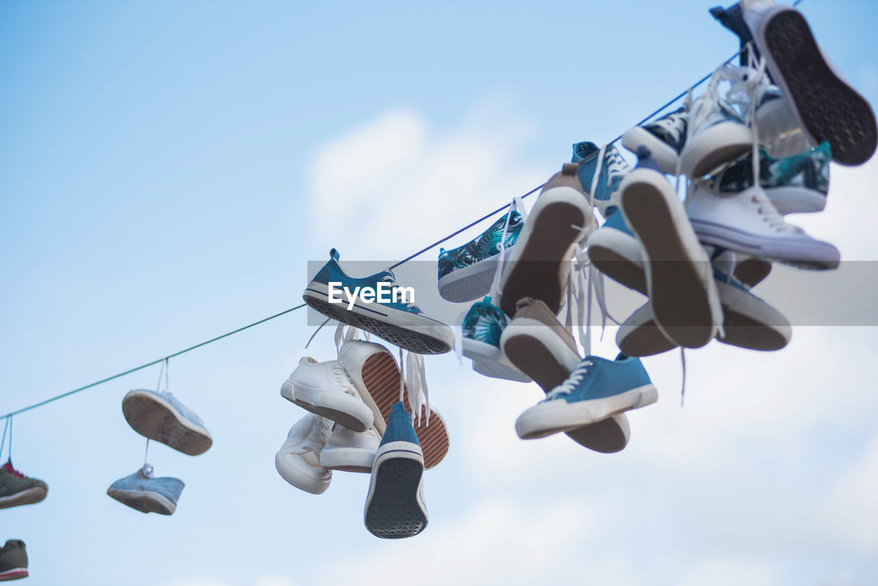 Pairs of sneakers and shoes hanging on cable