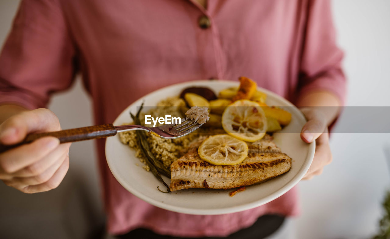 Midsection of woman holding food in plate