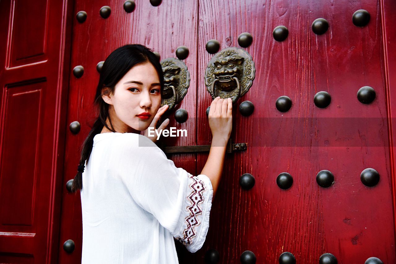 Rear view of woman holding door knocker