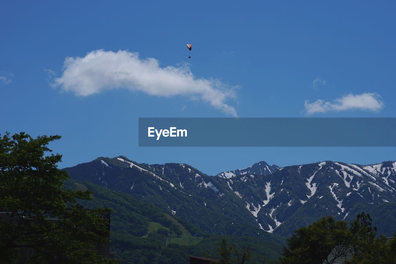 LOW ANGLE VIEW OF VAPOR TRAIL OVER MOUNTAIN AGAINST BLUE SKY