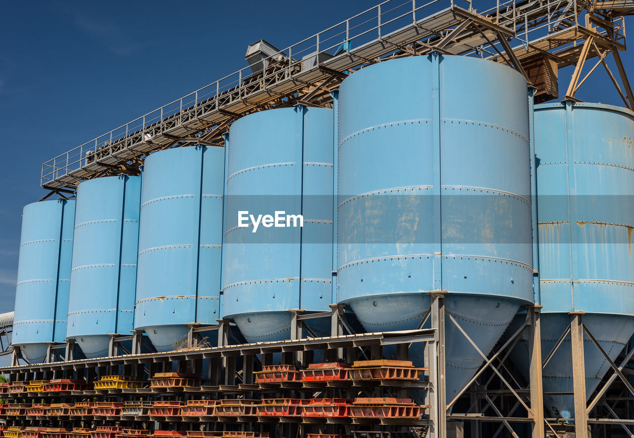 Big blue metallic industrial silos for the production of cement at an industrial cement plant