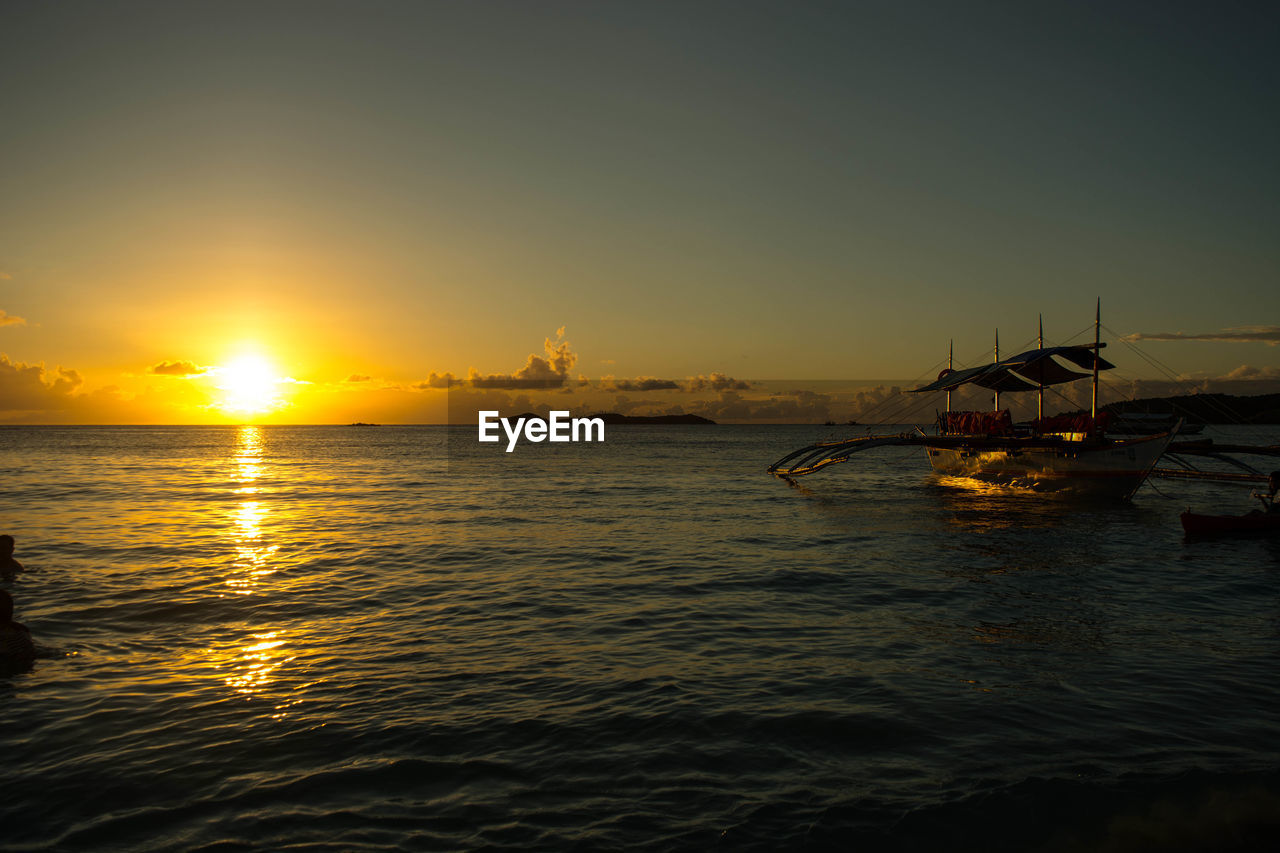 Boat moored on sea against sky during sunset