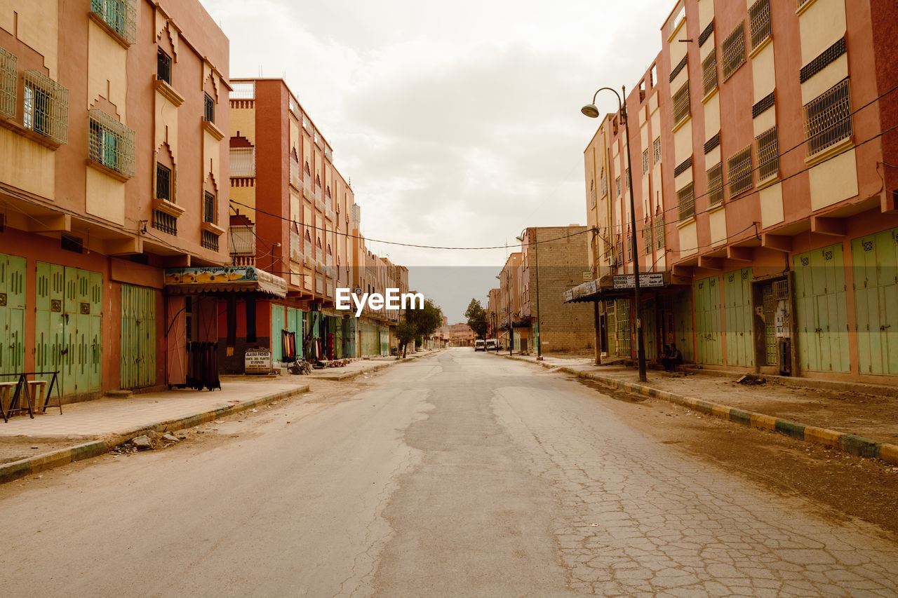 Empty road amidst buildings in city