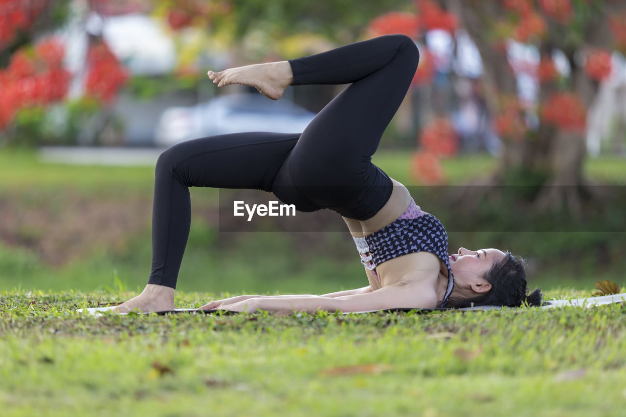 Full length of woman practicing yoga on exercise mat in park